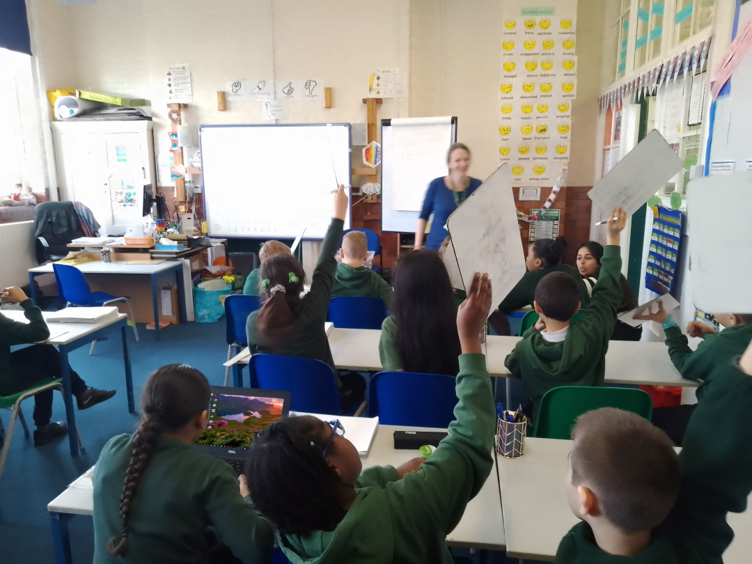 Children In Classroom With Hands Up